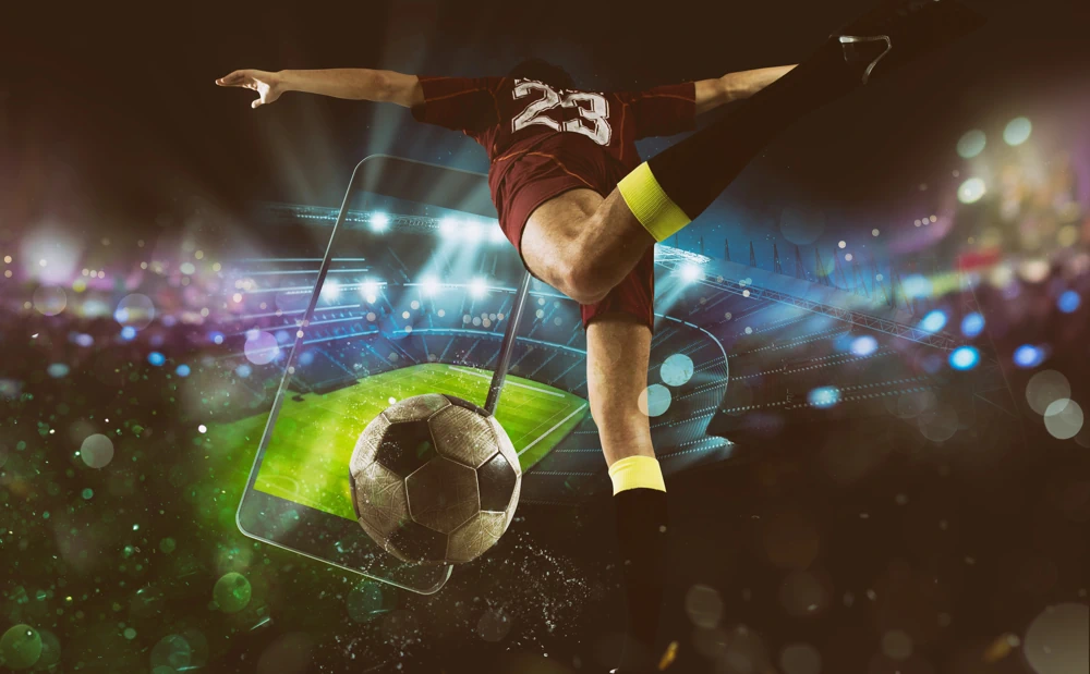 Footballer kicking ball with phone and stadium in background