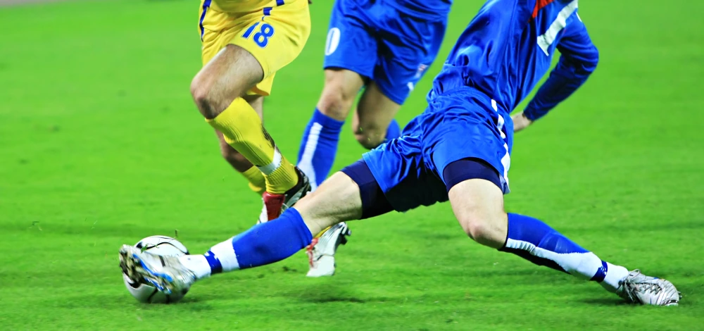 A football player about to get injured when stretching out his leg too far