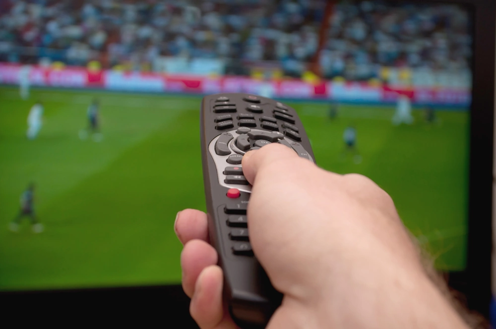 Remote pointing to TV showing football